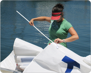 A woman in green shirt holding white sail.