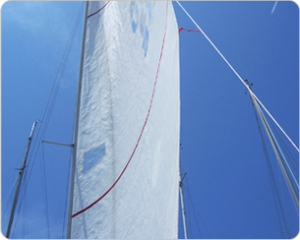 A sail boat is shown against the blue sky.