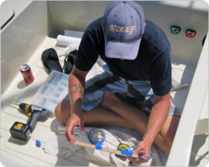 A man in blue shirt and hat working on a boat.