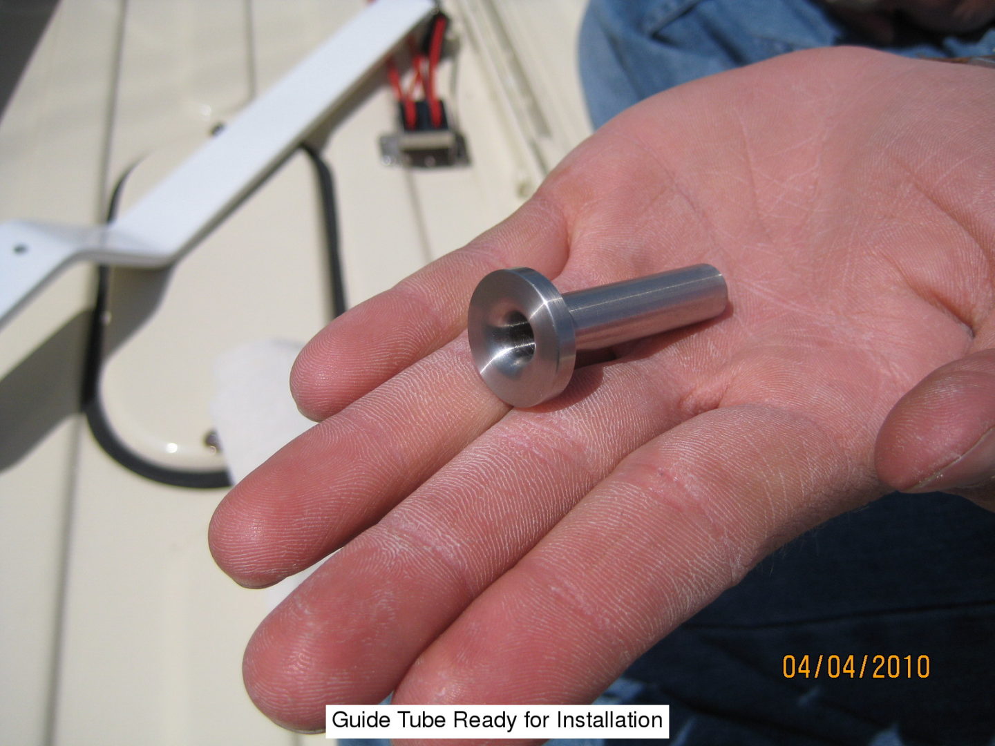 A hand holding a metal tube in its palm.