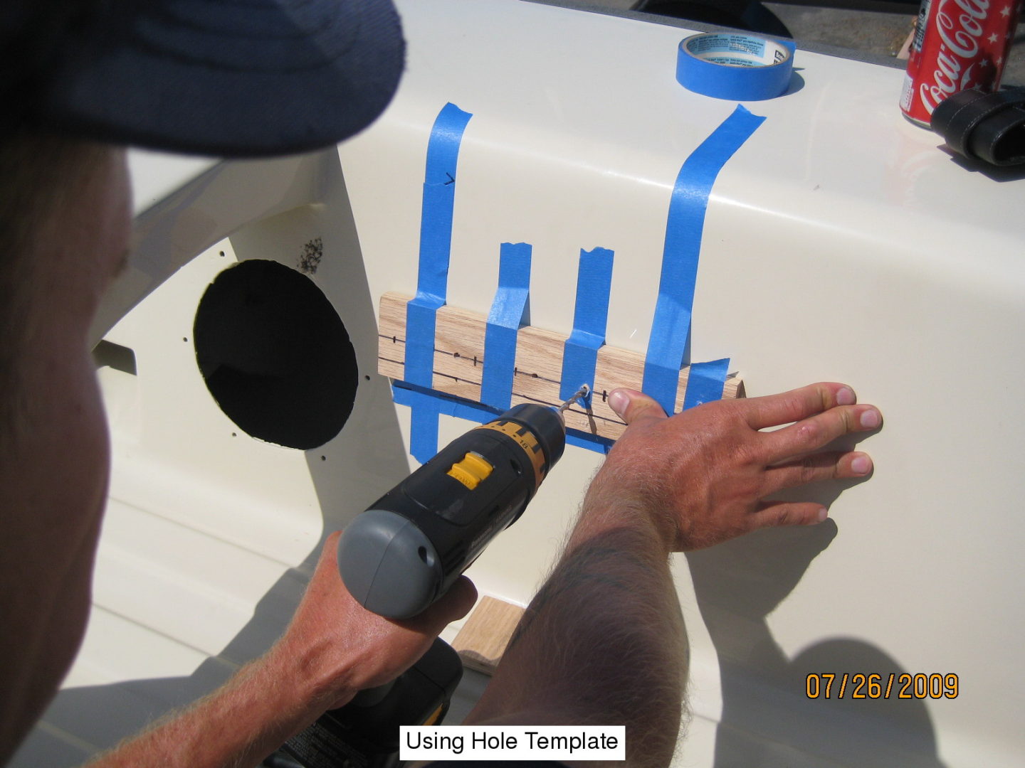 A person using a drill to cut tape off the bottom of a boat.