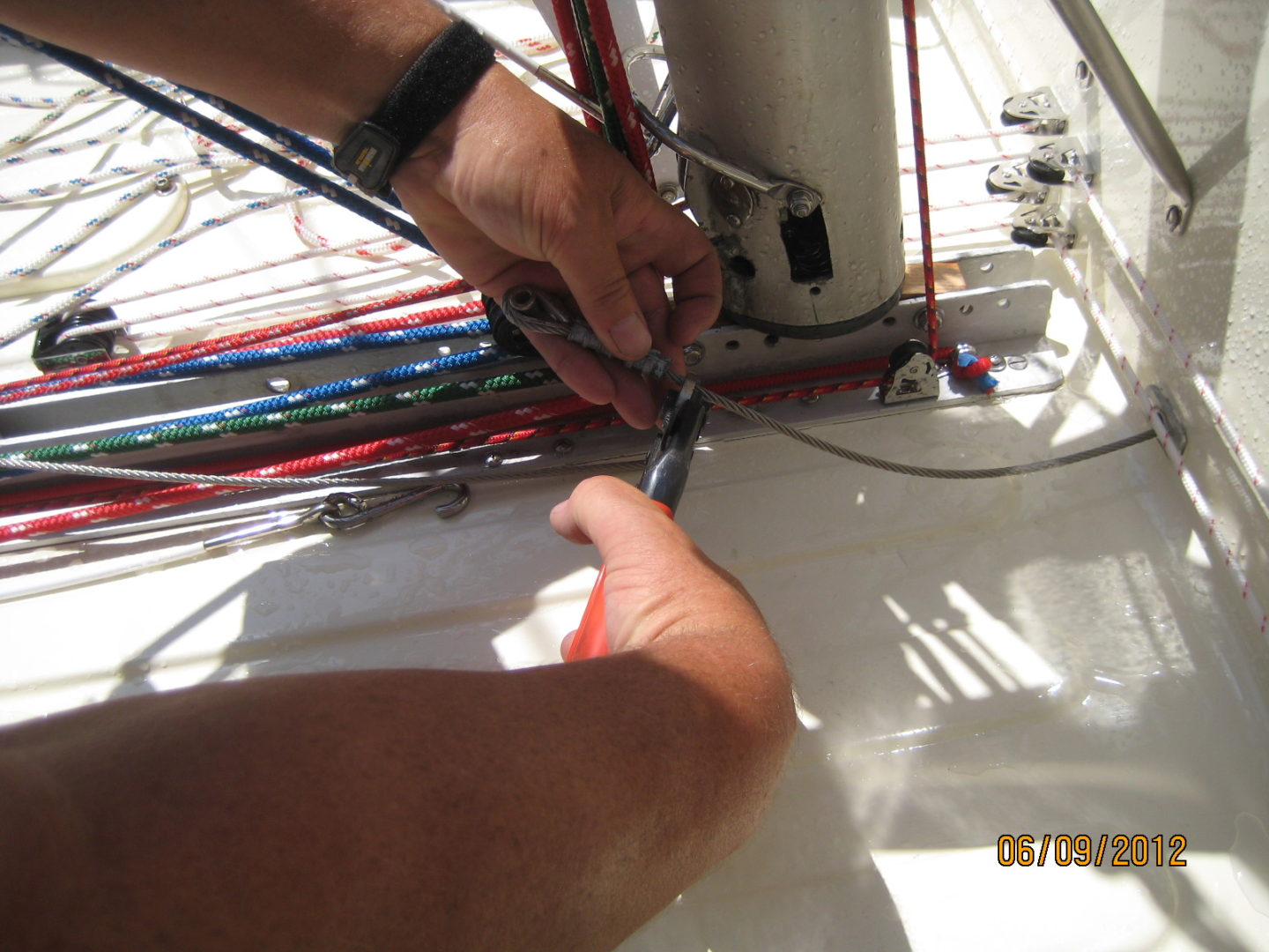 A person cutting wires on the side of a boat.