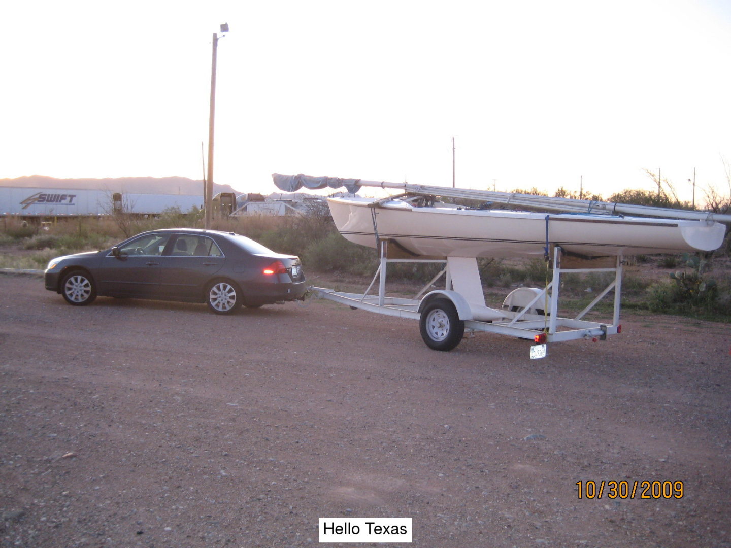 A boat is being towed behind a car.