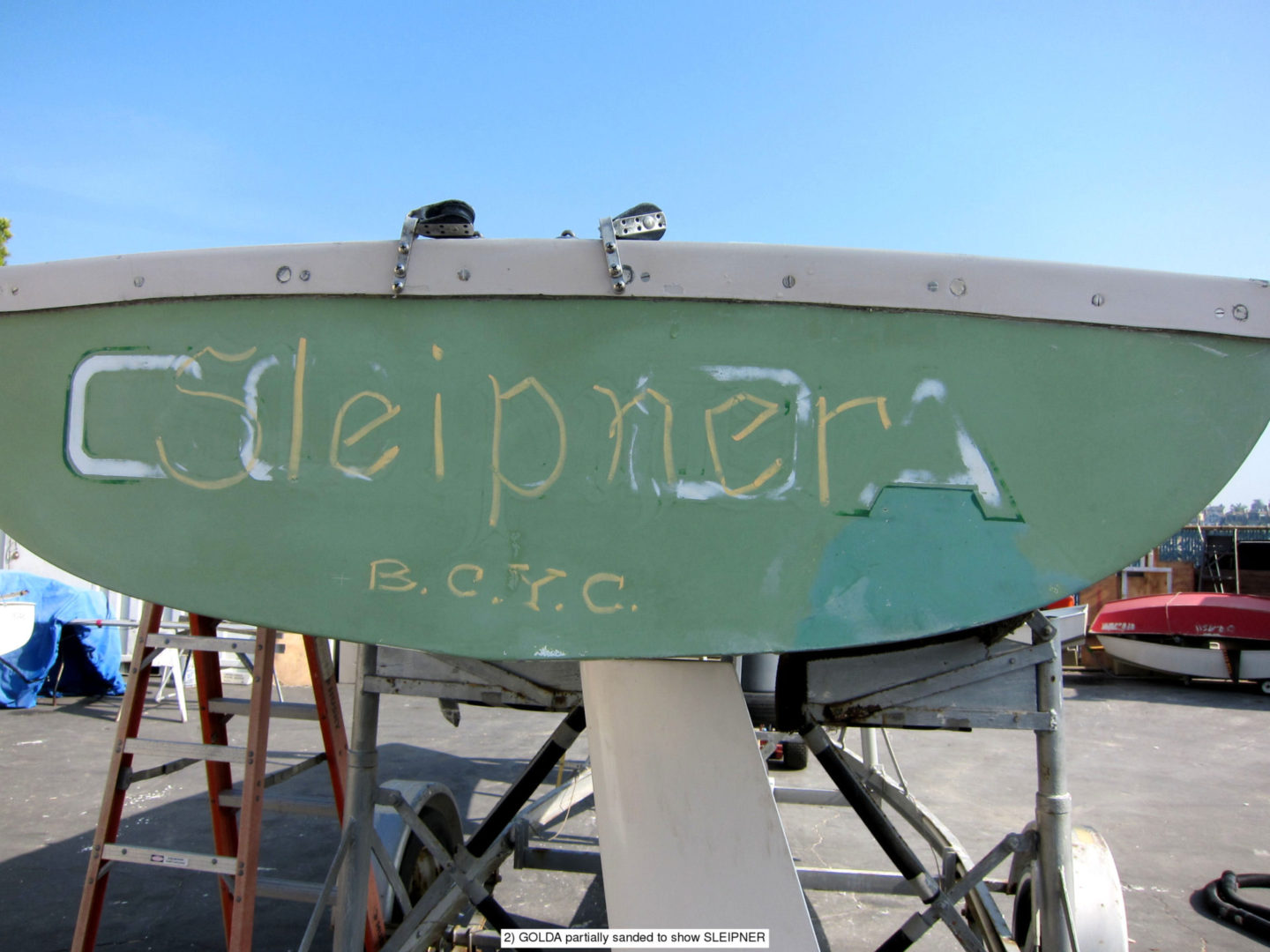 A boat with graffiti on it is sitting in the sun.