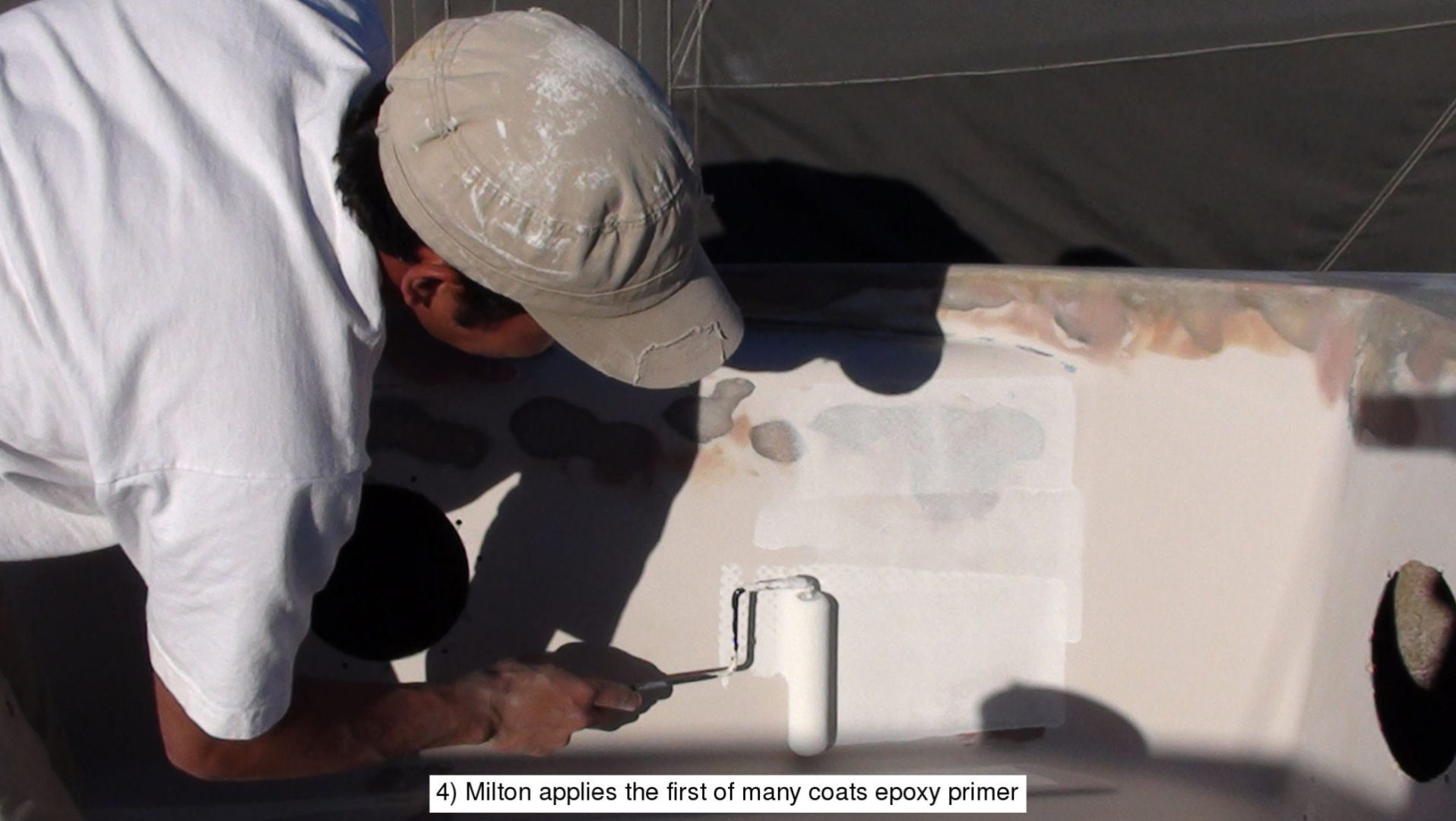 A man painting a white object with a spray paint gun.