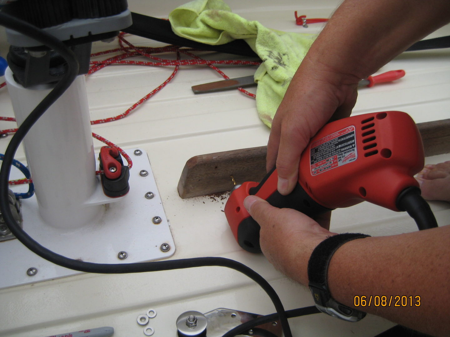 A person using an electric saw on the side of a boat.