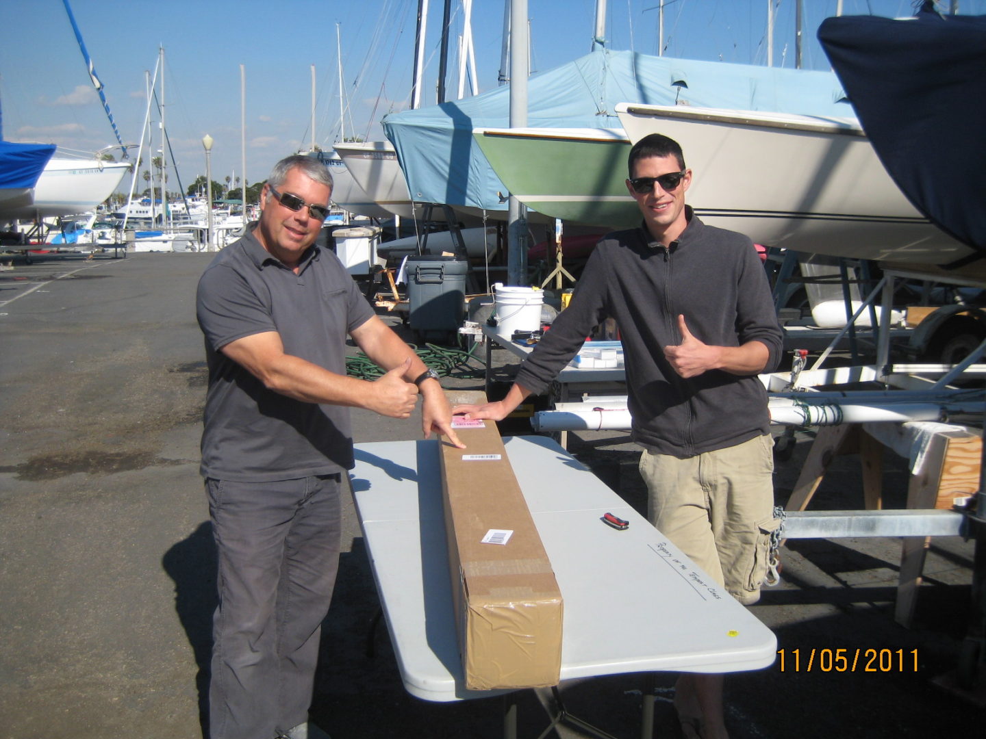 Two men standing next to a boat in the water.