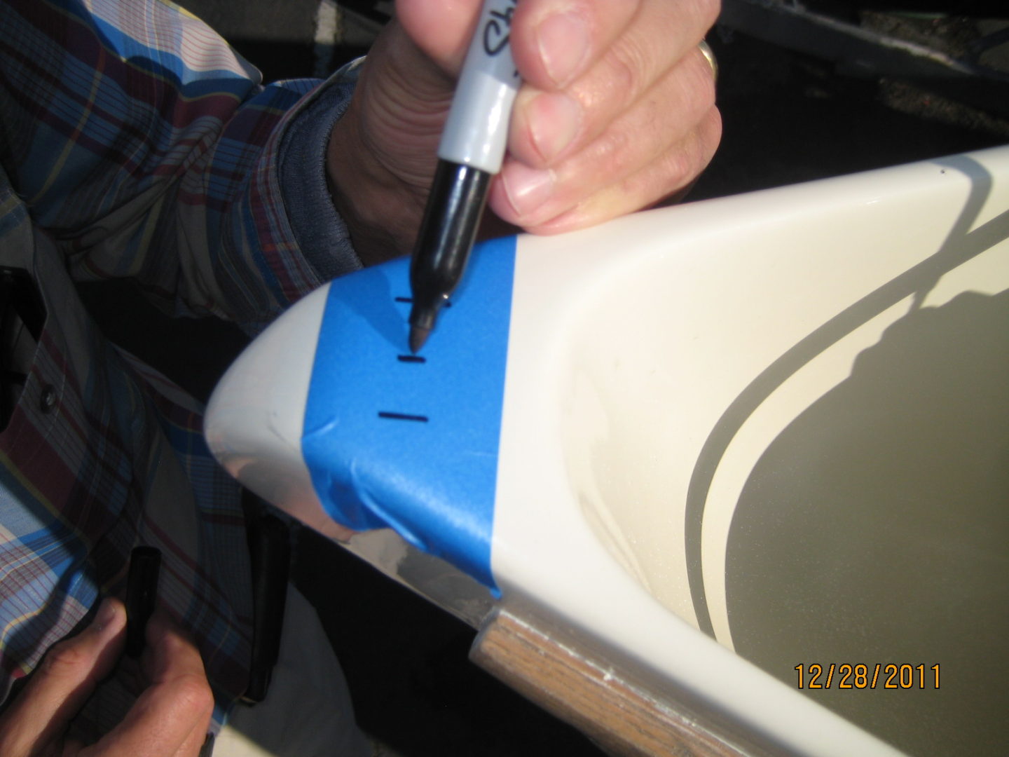 A person painting the edge of a sink.