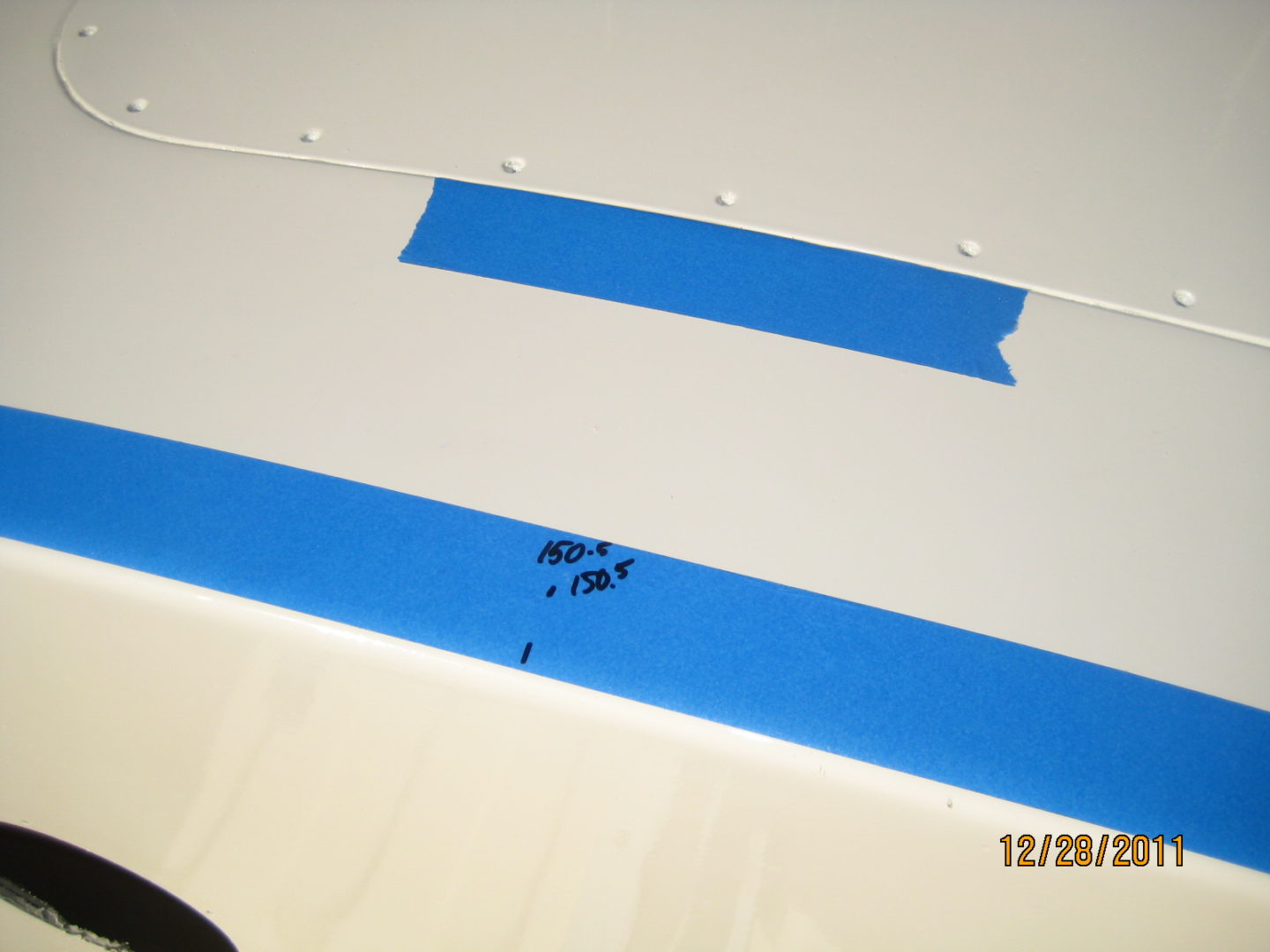 A blue strip is taped to the side of a white surface.