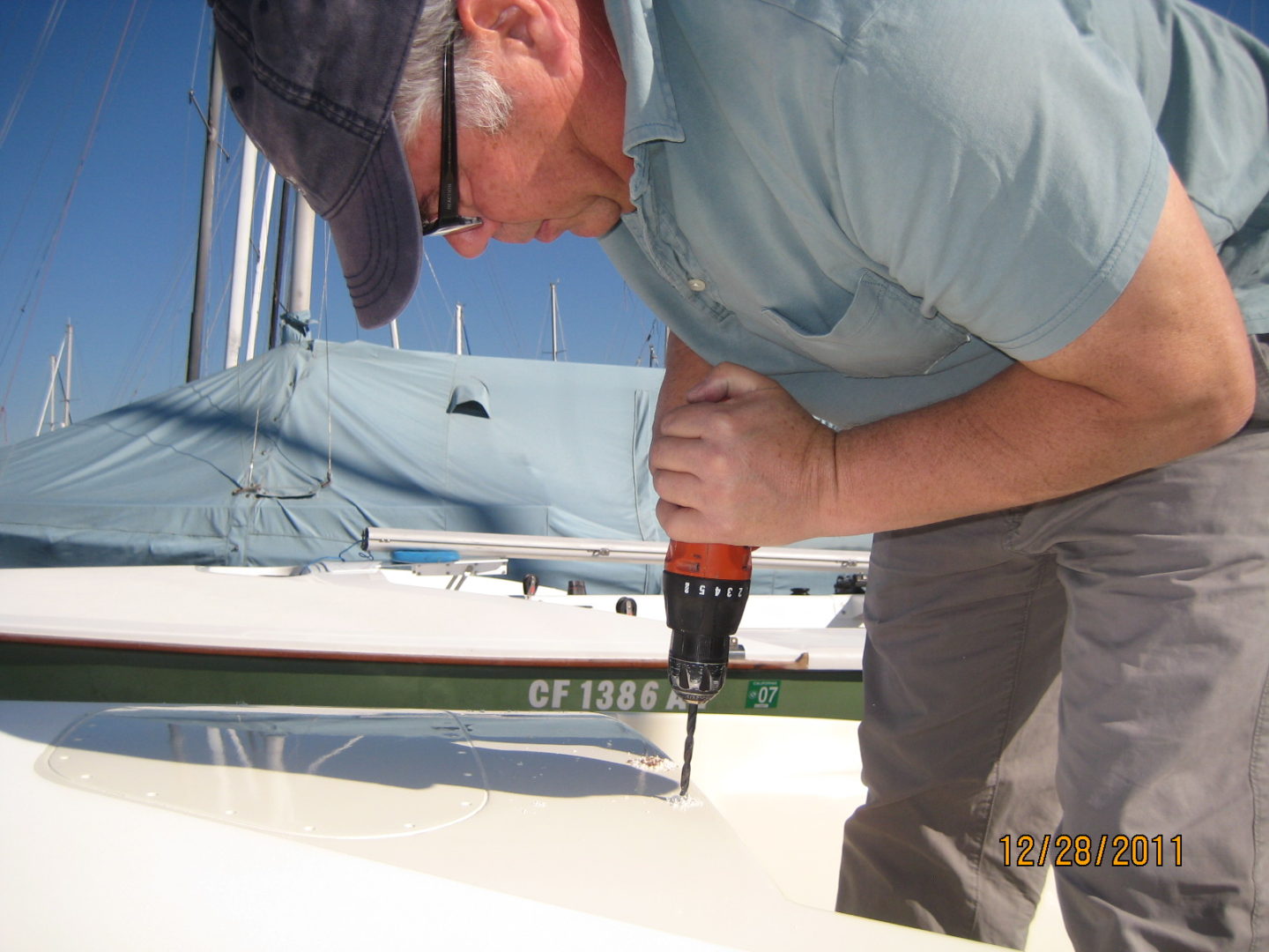 A man with a drill on the side of a boat.