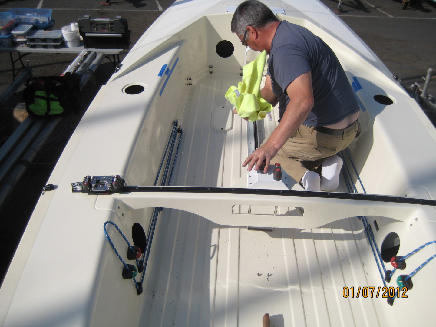 A man in blue shirt and yellow vest standing on top of boat.