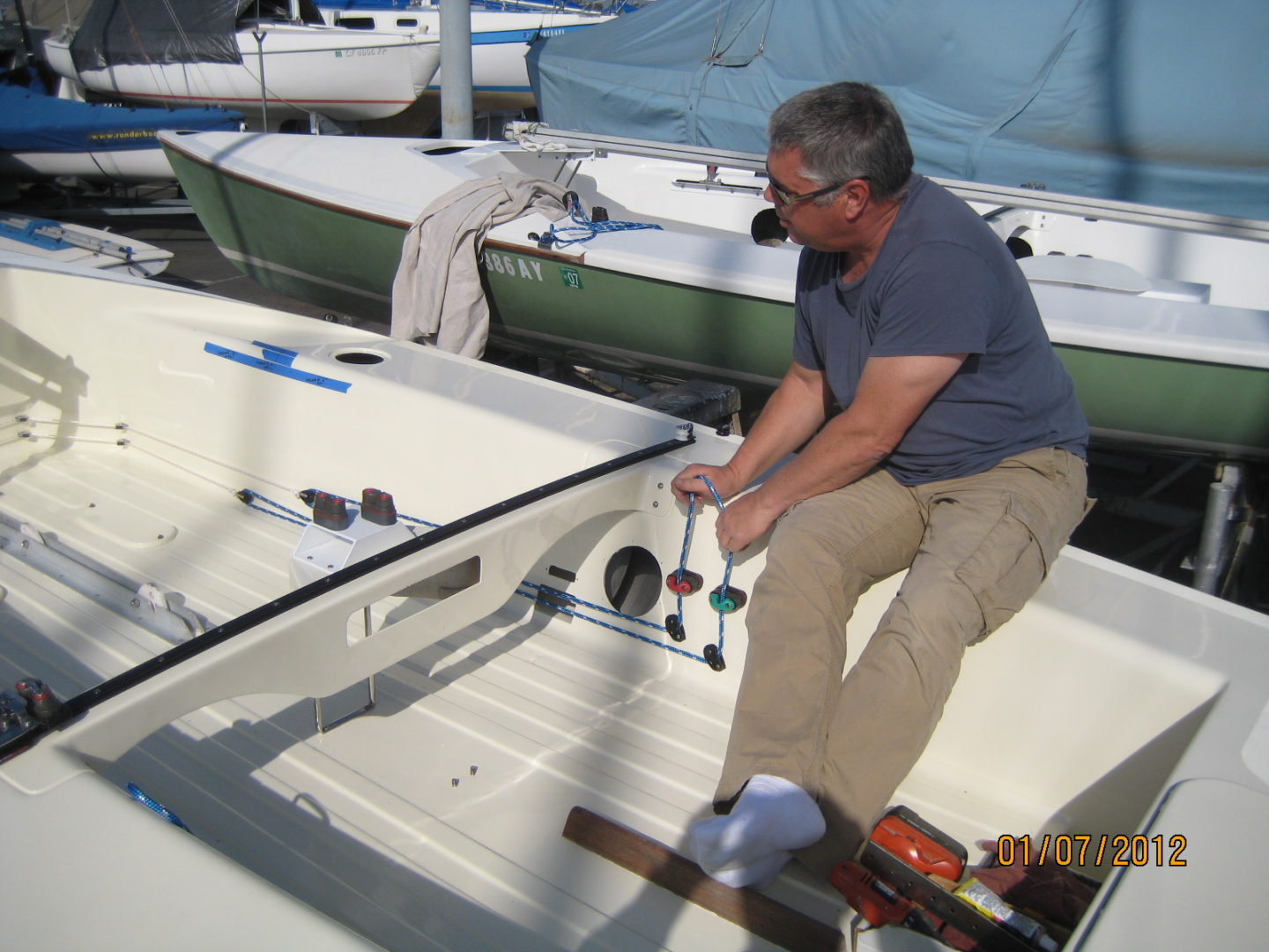 A man in blue shirt and tan pants sitting on boat.