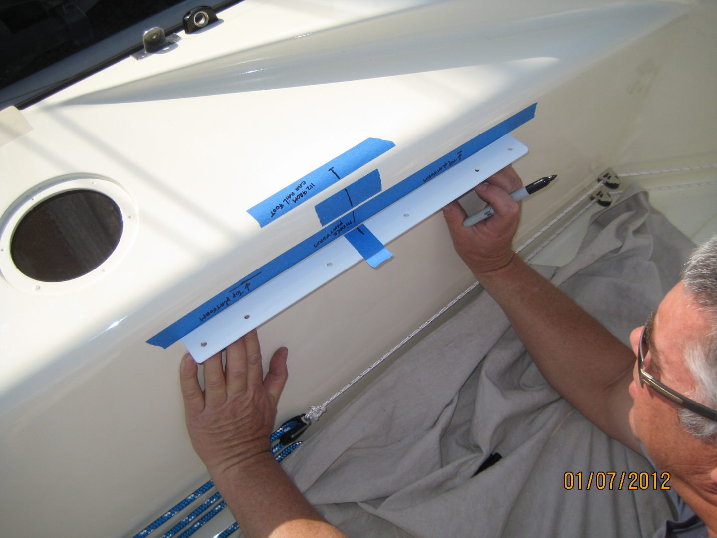 A person is holding the blue tape on the side of a boat.