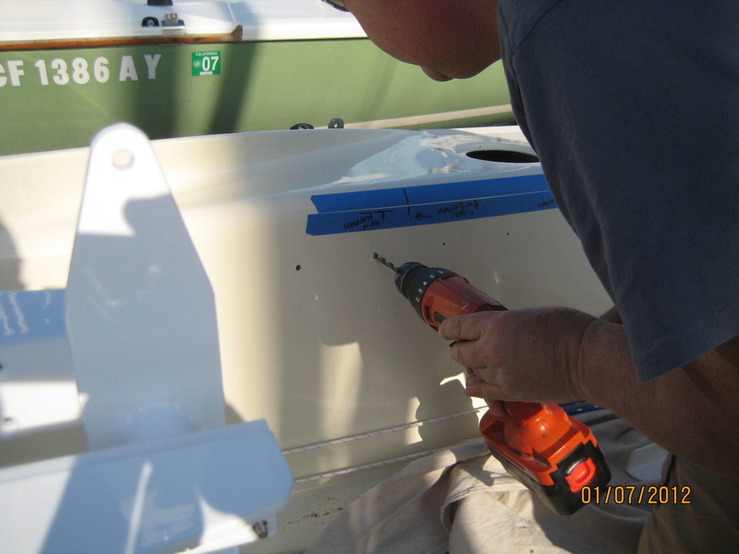 A man using an orange drill to attach the cover on a boat.