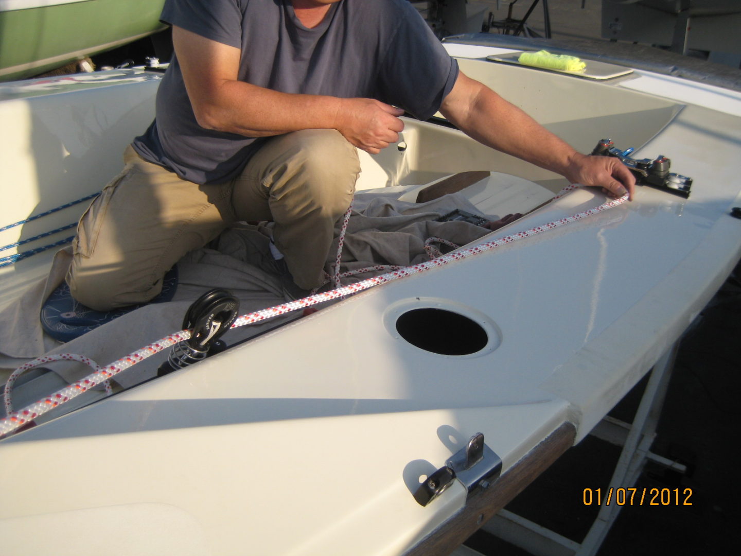 A man is working on the sail of his boat.