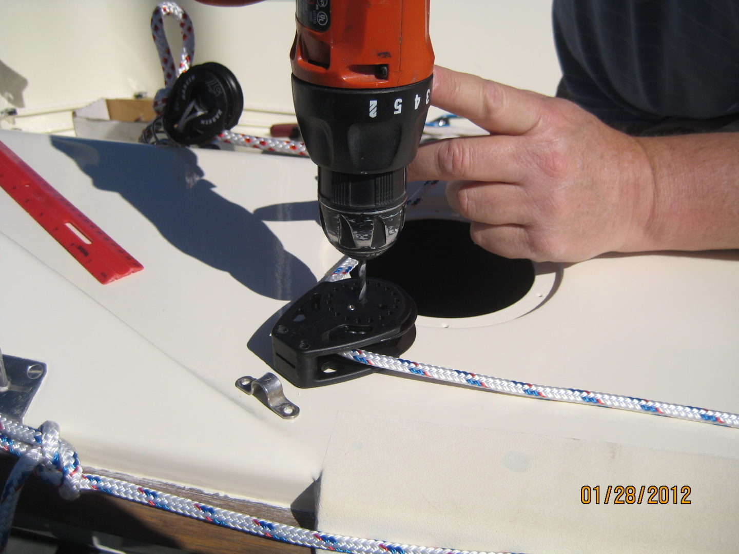 A person using a drill to install the cable on a boat.