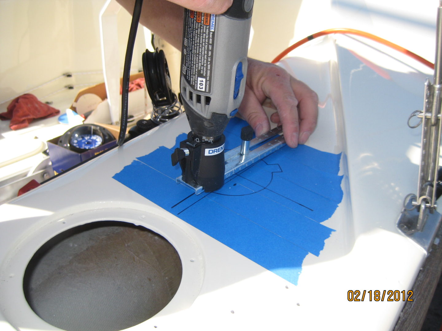 A person using a drill to cut out the blue paper.