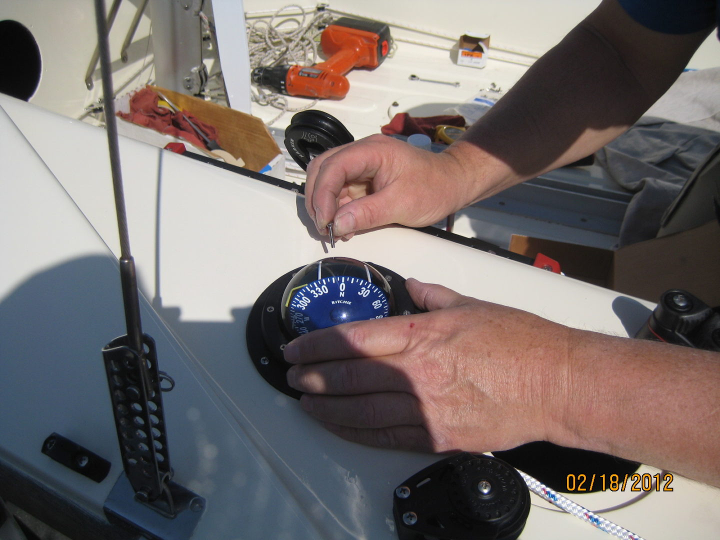 A person holding a compass on top of a boat.