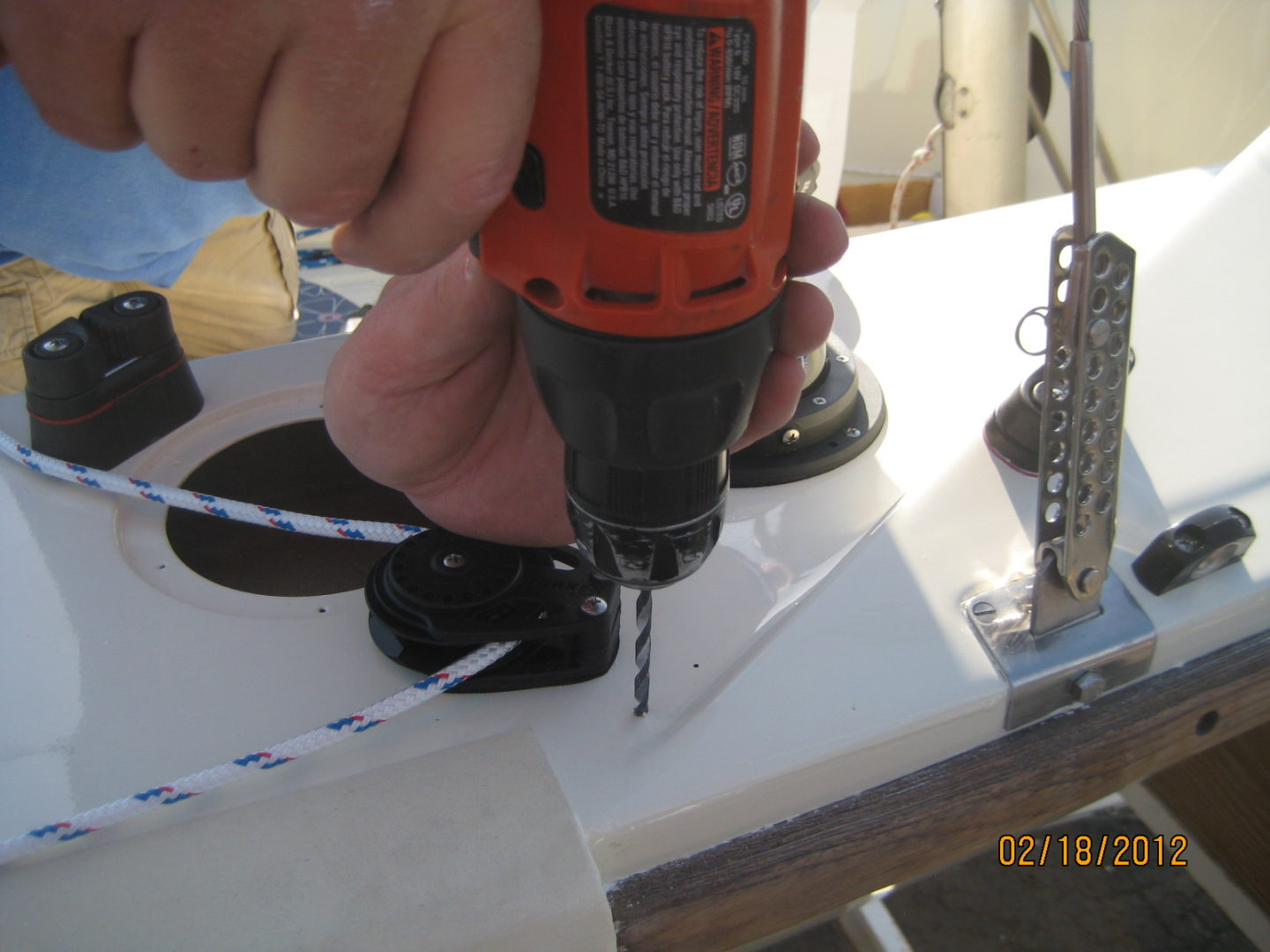 A person using an electric drill to make holes in the ground.