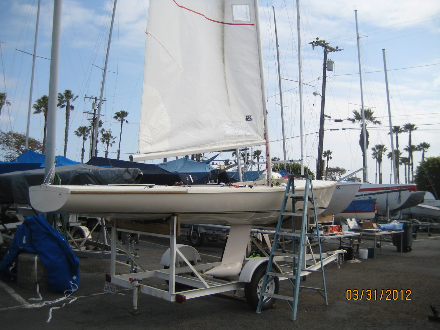 A boat is parked on the trailer in a lot.