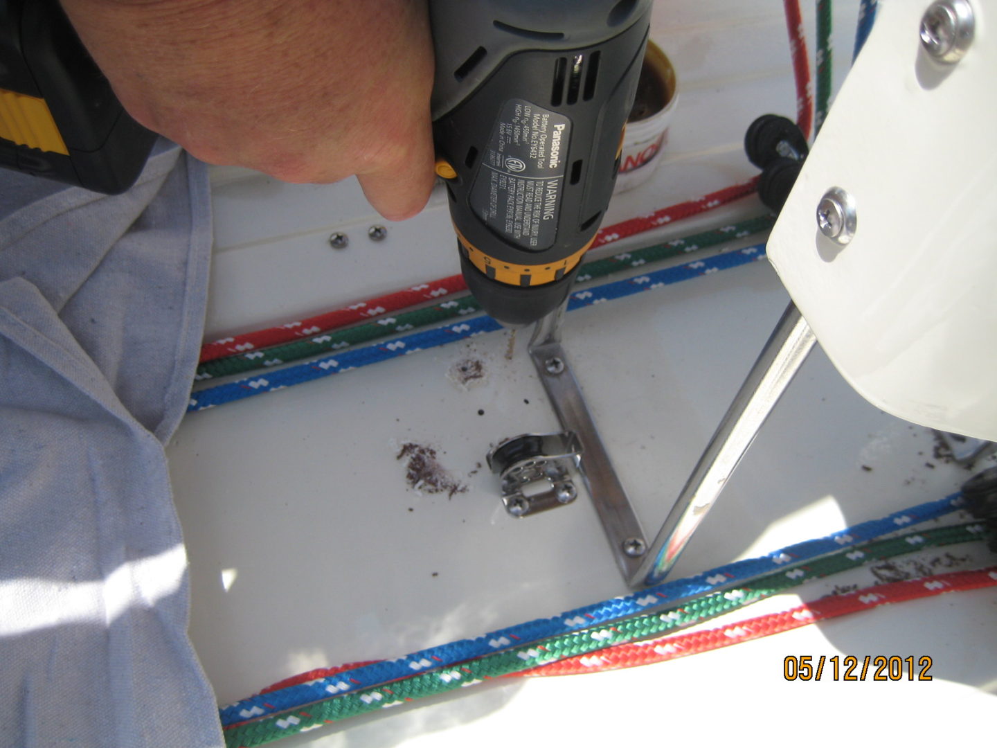 A person using an electric drill to fix the hole in the floor.