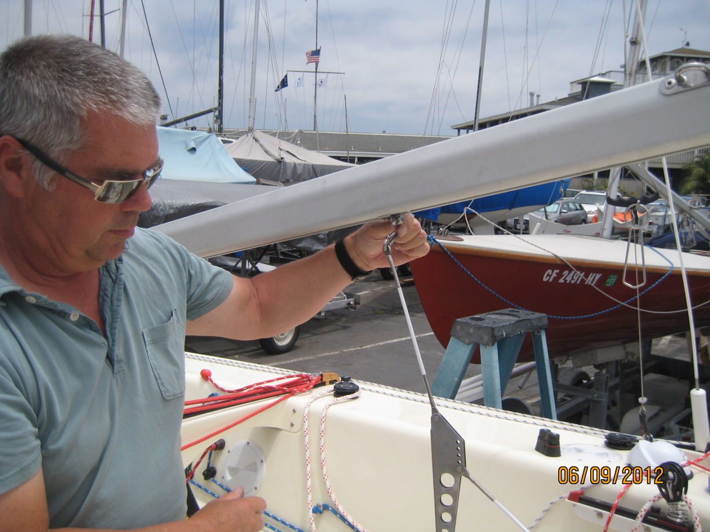 A man working on a sail boat in the water.