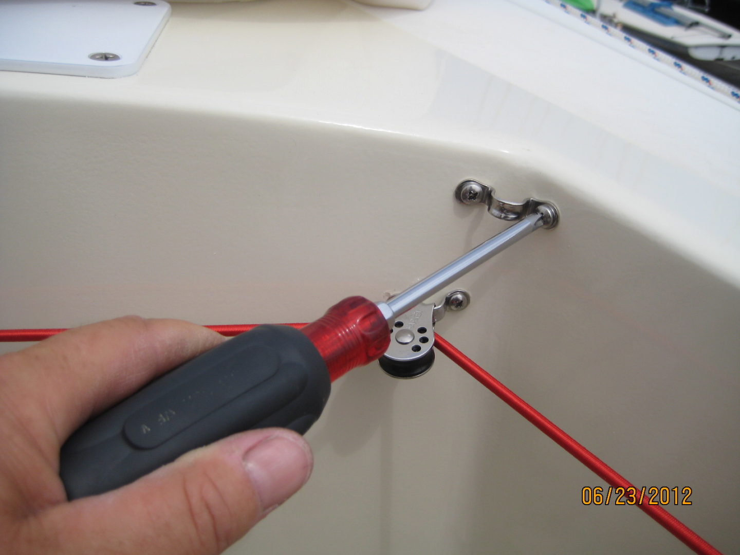 A person using a screwdriver to fix the hole in the bathtub.