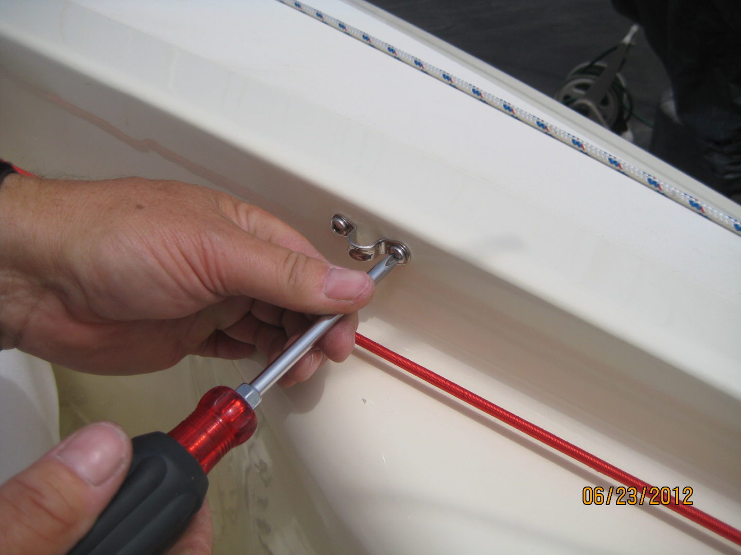 A person using a pair of red and black tools to fix the hole in the sink.