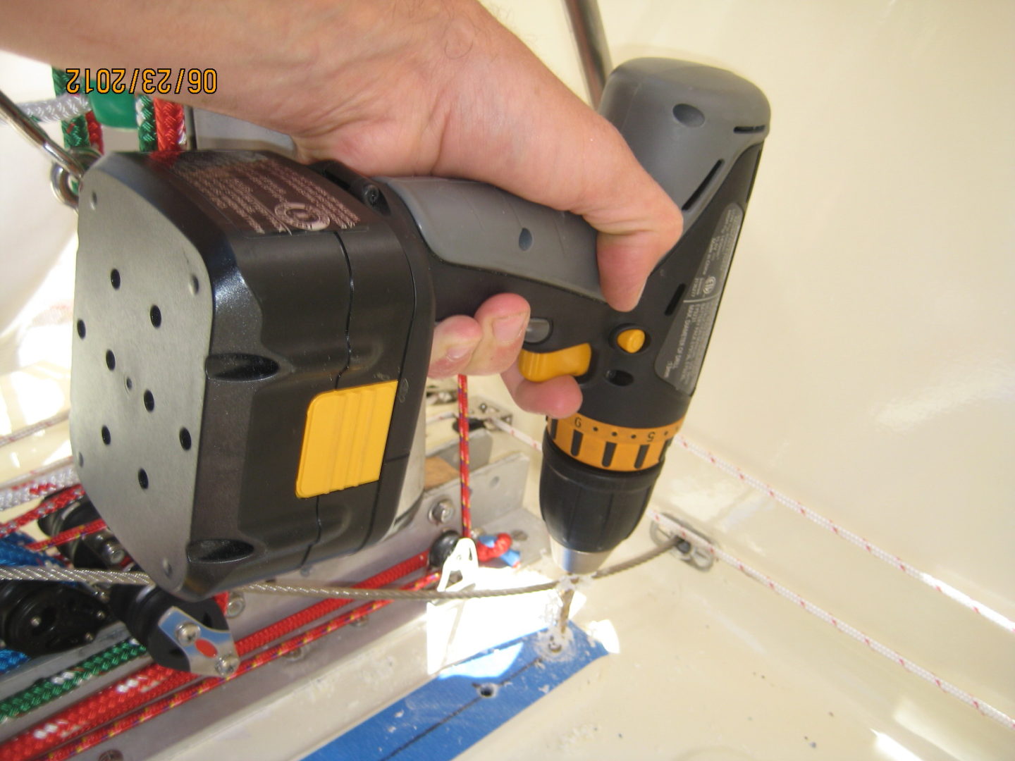 A person using a cordless drill to fix the electrical box.