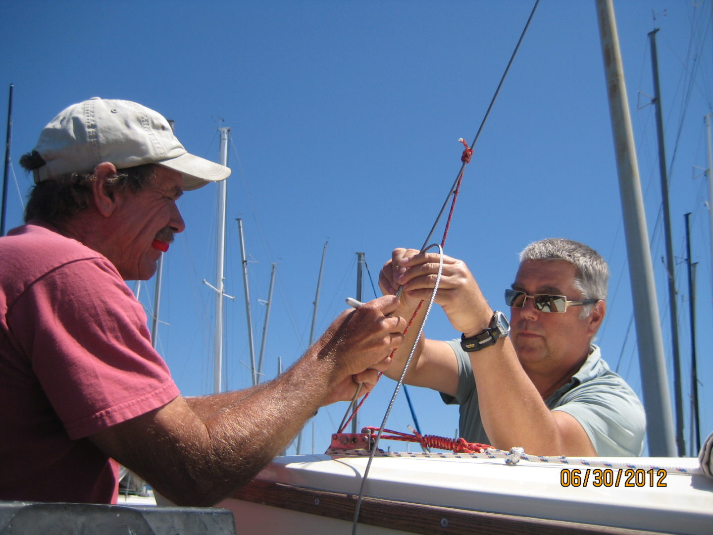 Two men are working on a sailboat.