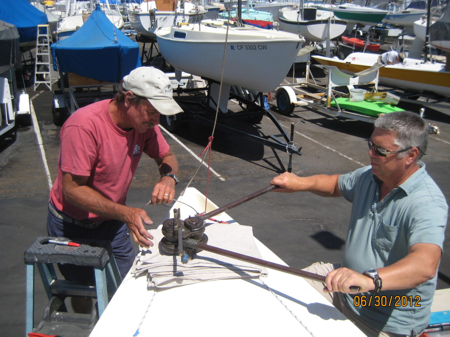 Two men sitting at a table with boats in the background.