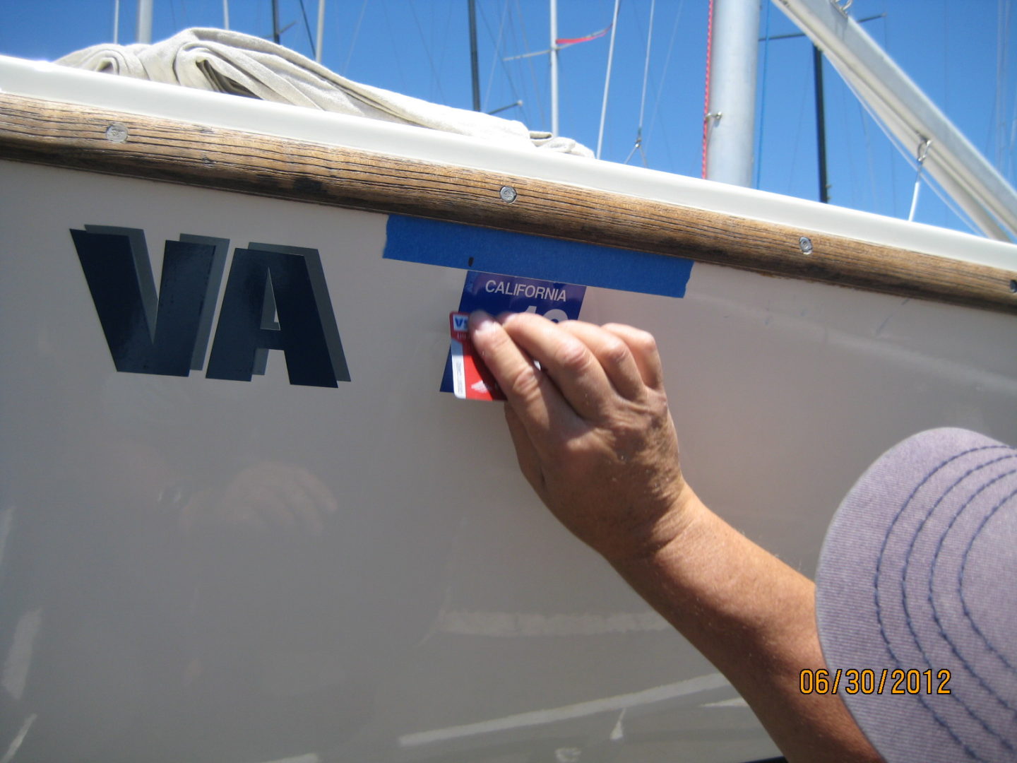 A person is putting stickers on the side of a boat.