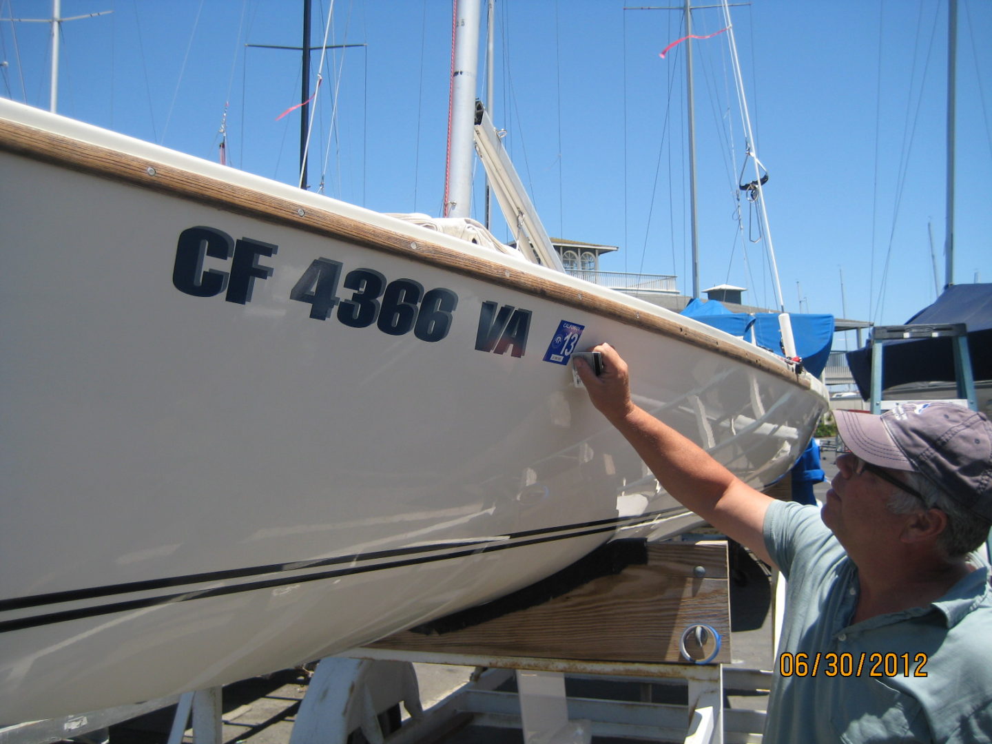 A man is painting the numbers on a boat.