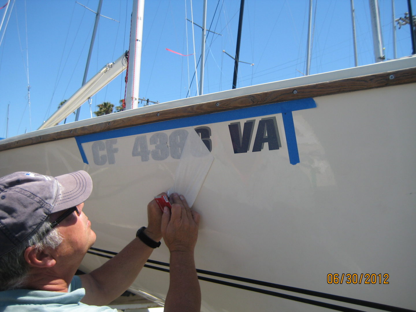 A man painting the side of a boat.