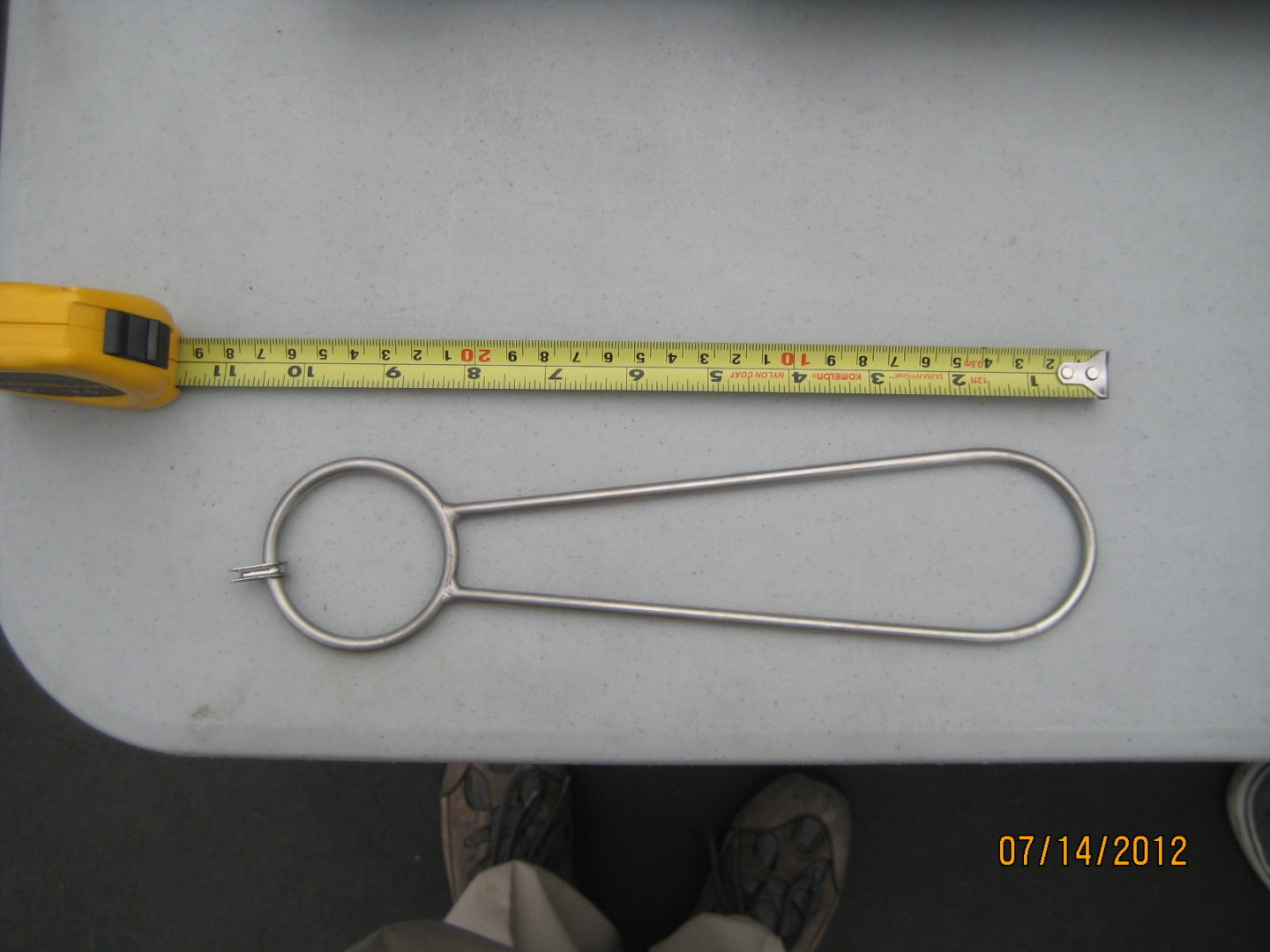 A metal object is shown next to a measuring tape.