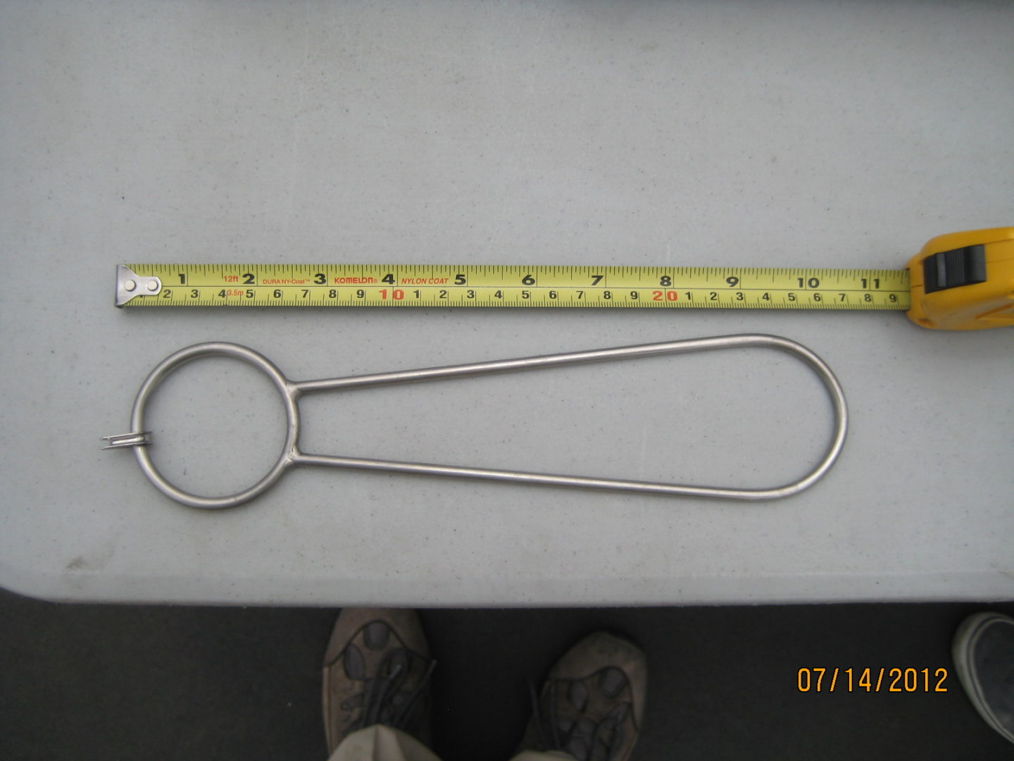 A metal object is shown next to a measuring tape.