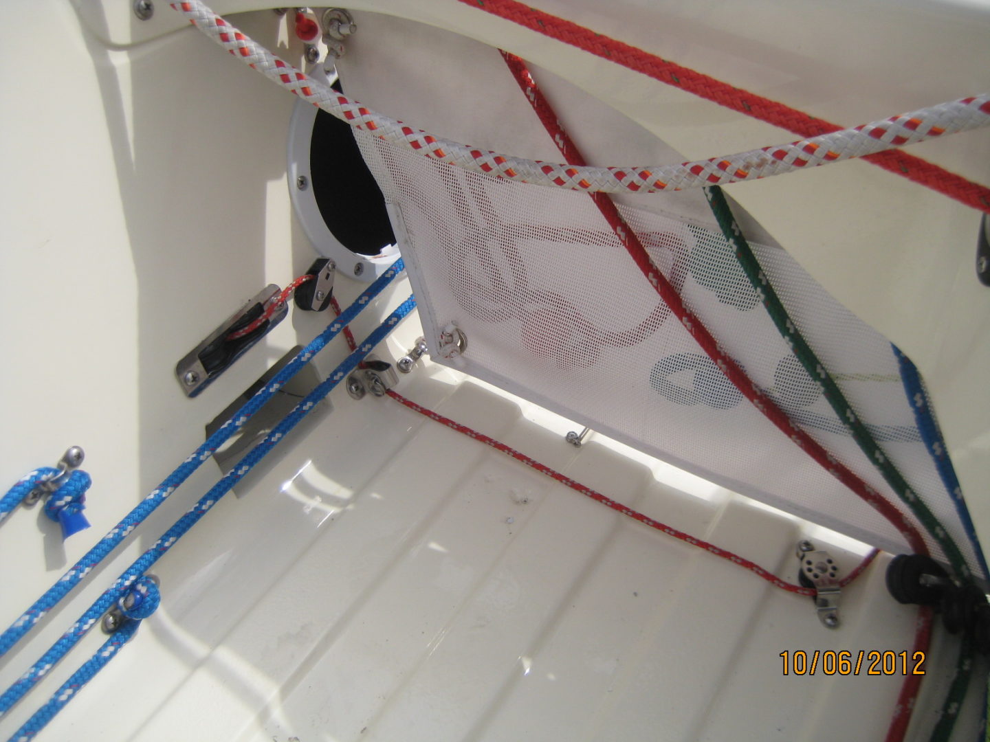 A white boat with red, blue and green ropes on the deck.