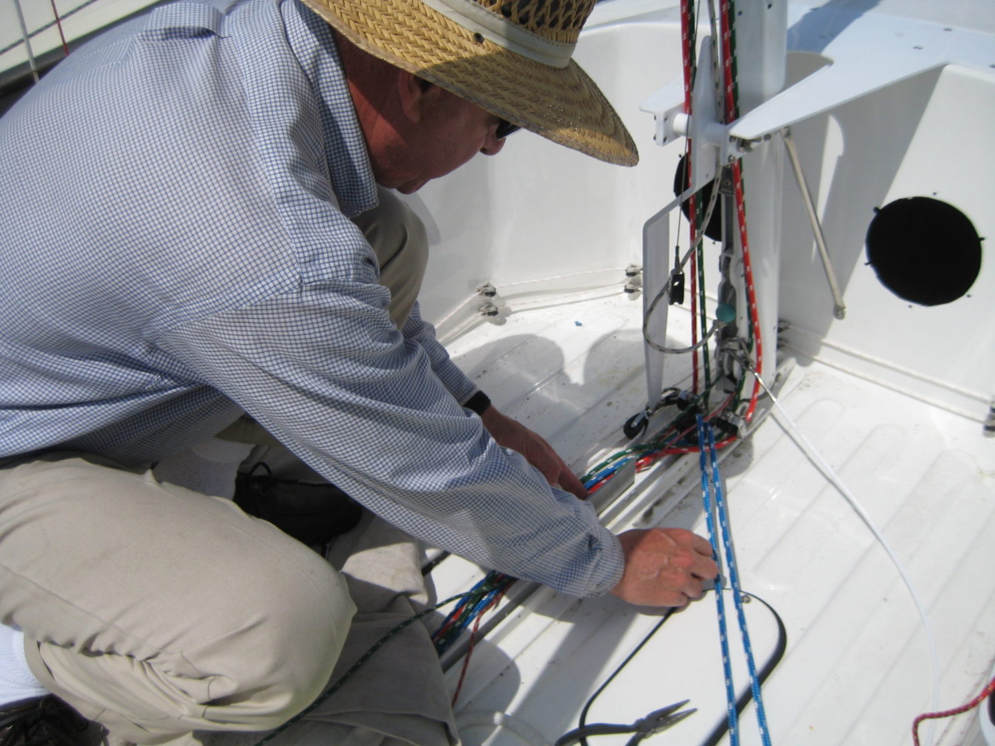 A man in a straw hat working on wires.