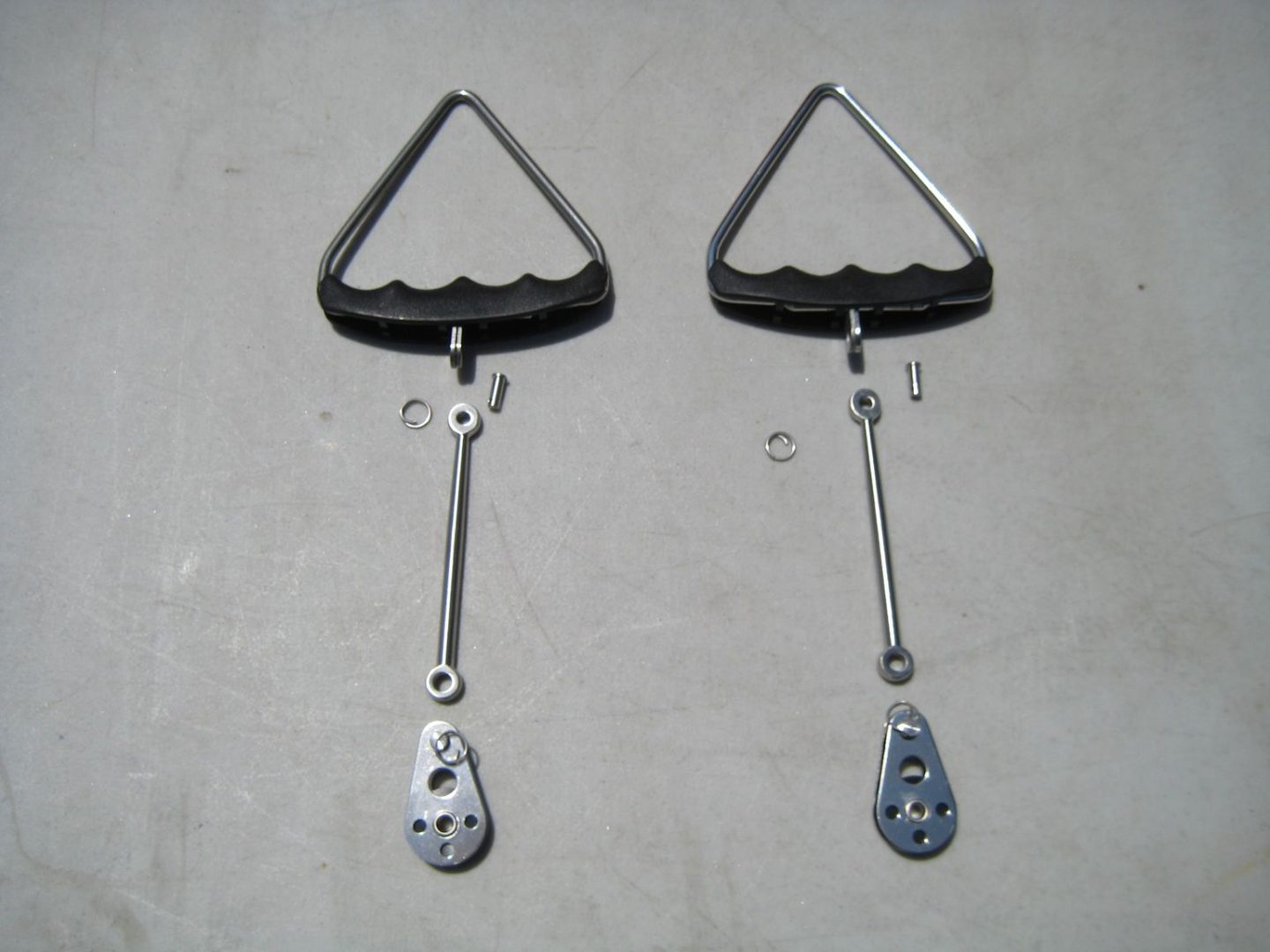 A pair of triangle shaped metal hooks with hanging chains.