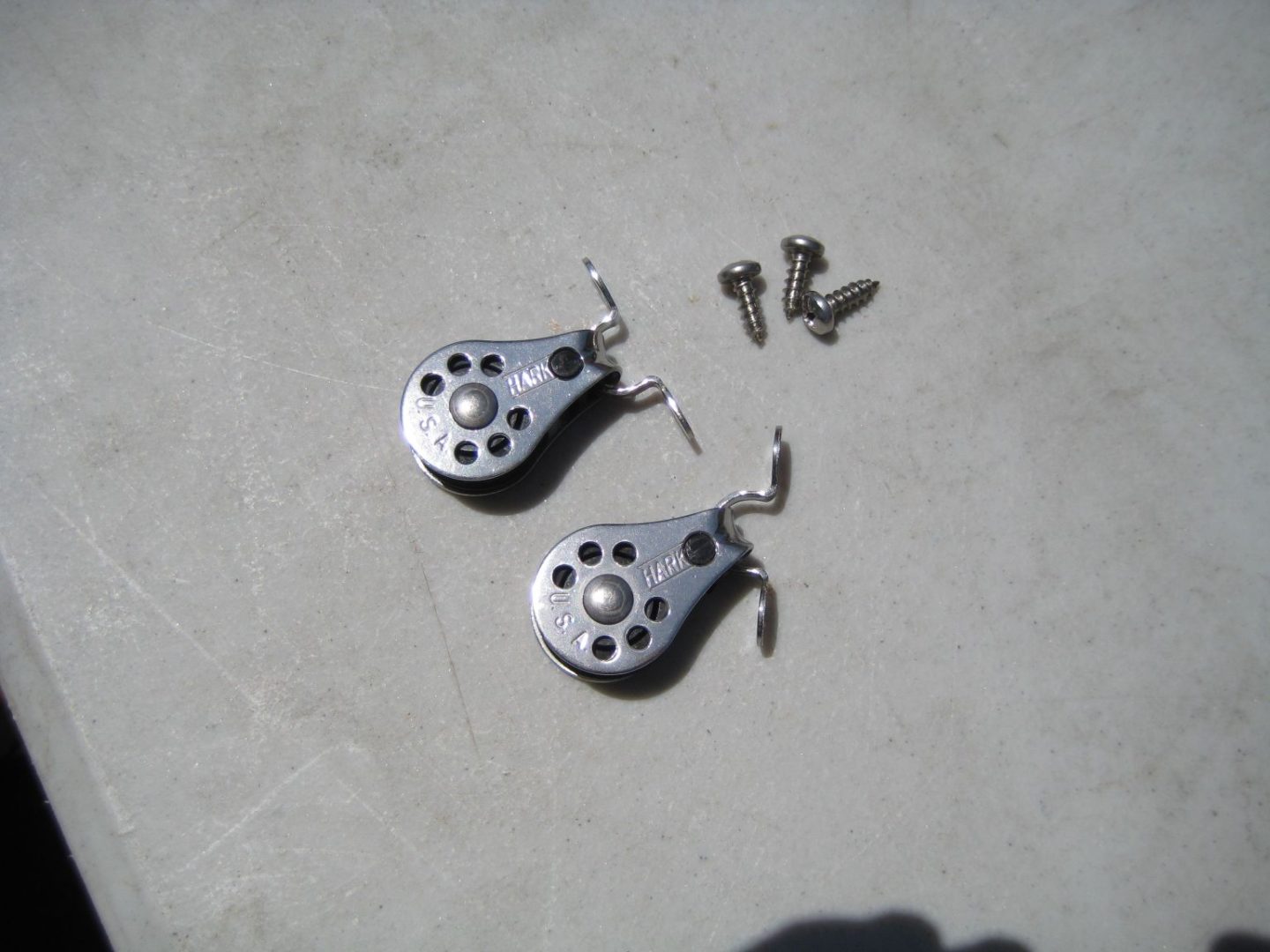 A pair of silver bells sitting on top of a cement floor.