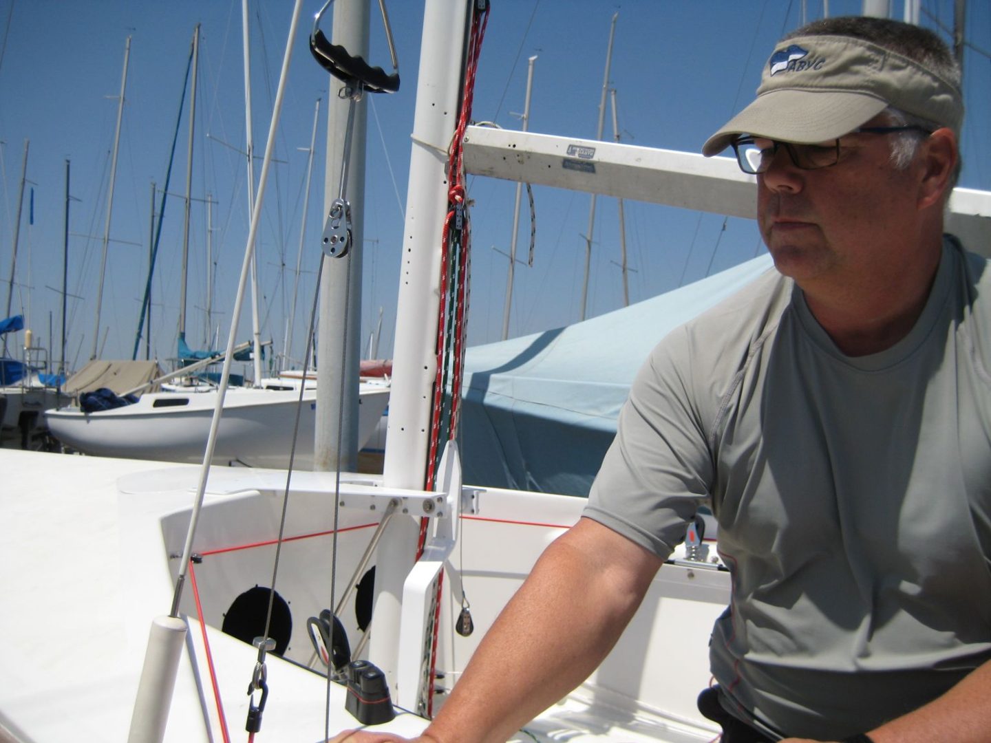 A man in grey shirt on boat with boats.