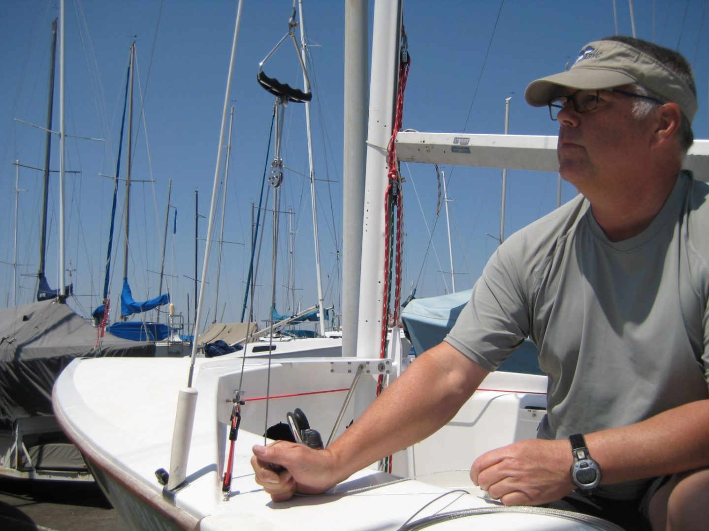 A man sitting on the side of a boat in front of some boats.