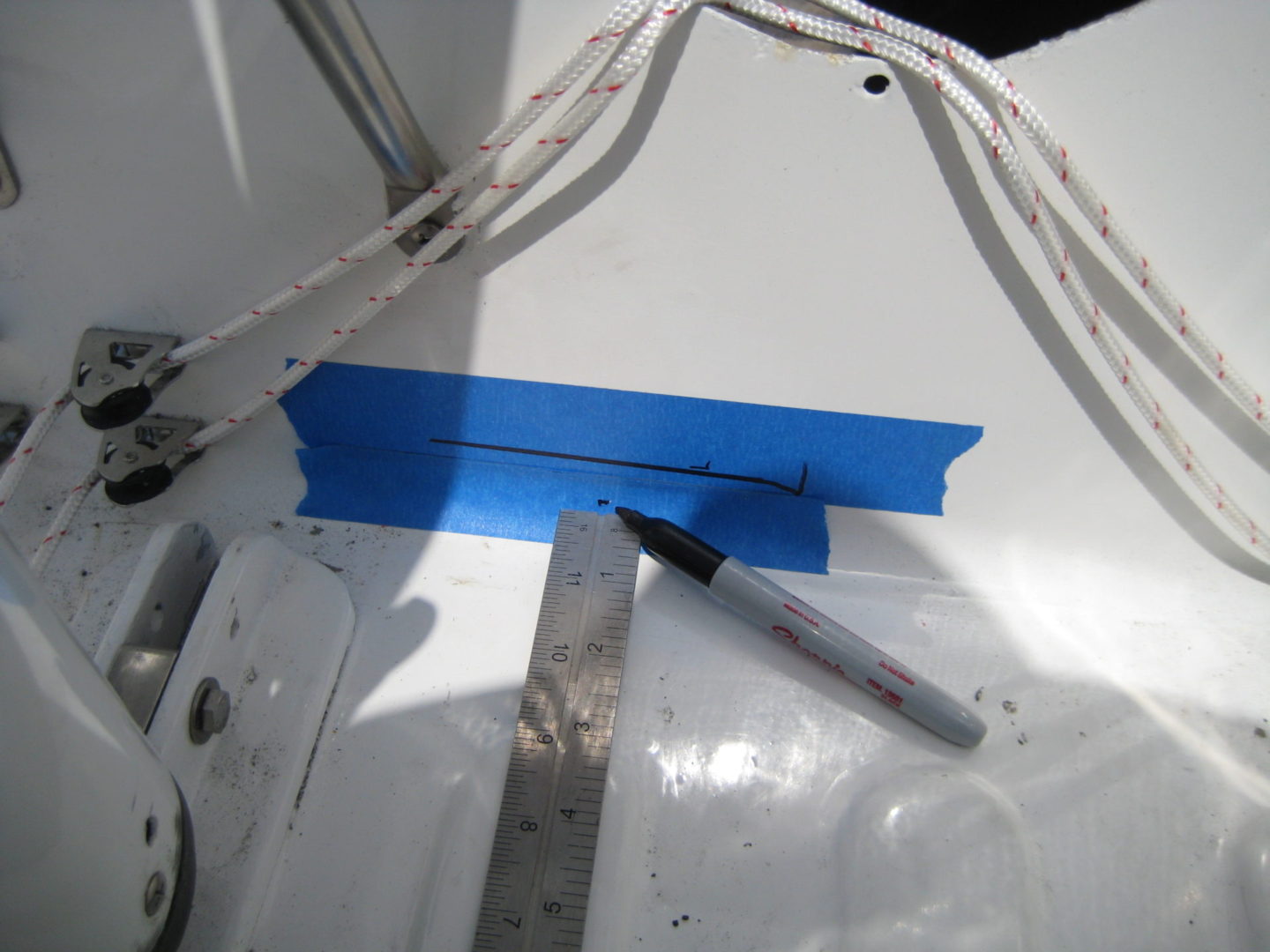 A blue strip is being cut out of the side of a boat.