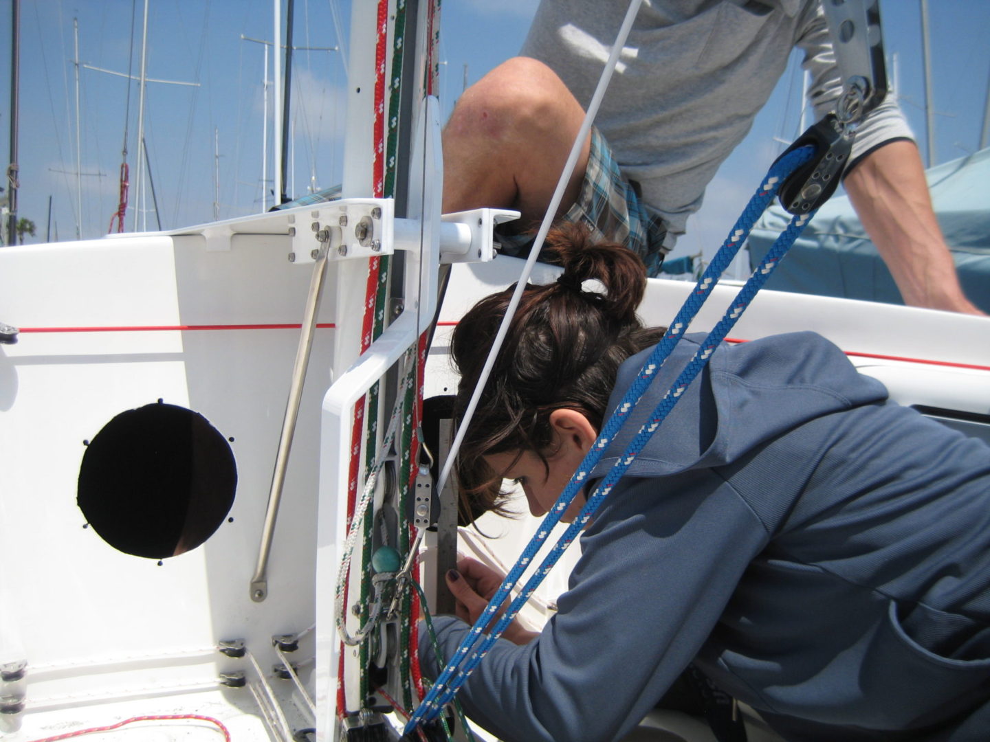 A man and woman working on the side of a boat.