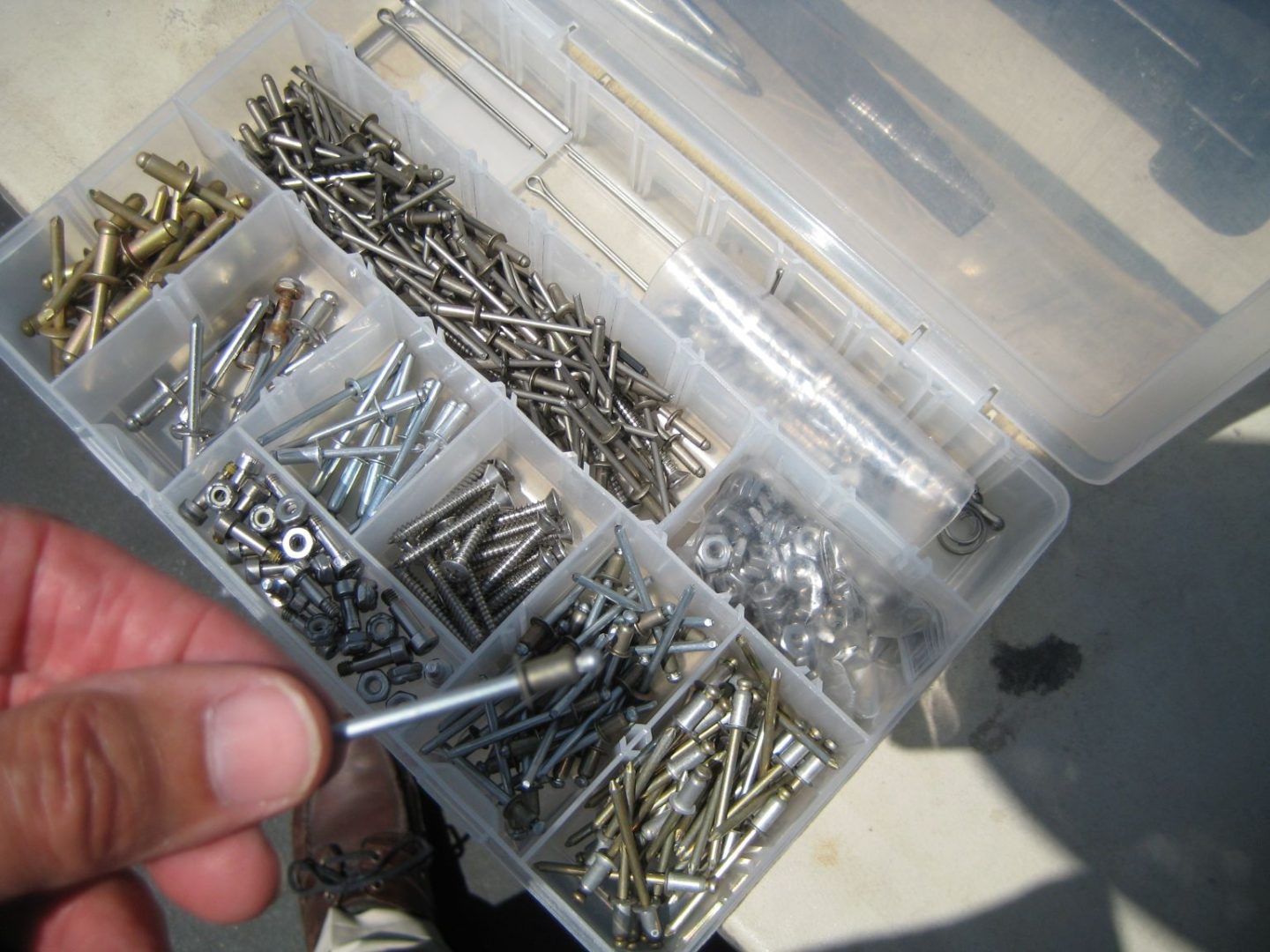 A person holding a box of nails and screws.