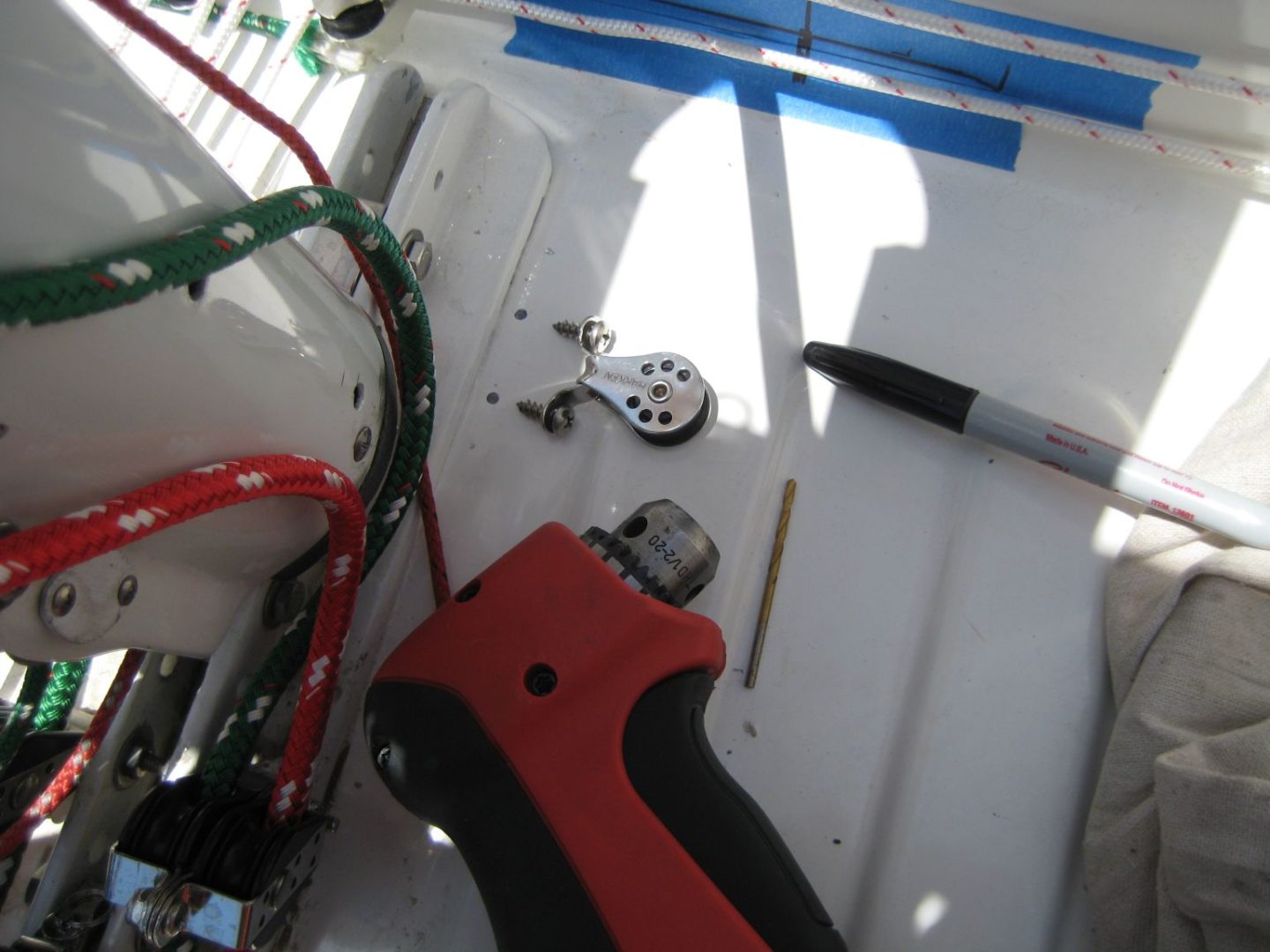 A red and black tool sitting on top of a white board.