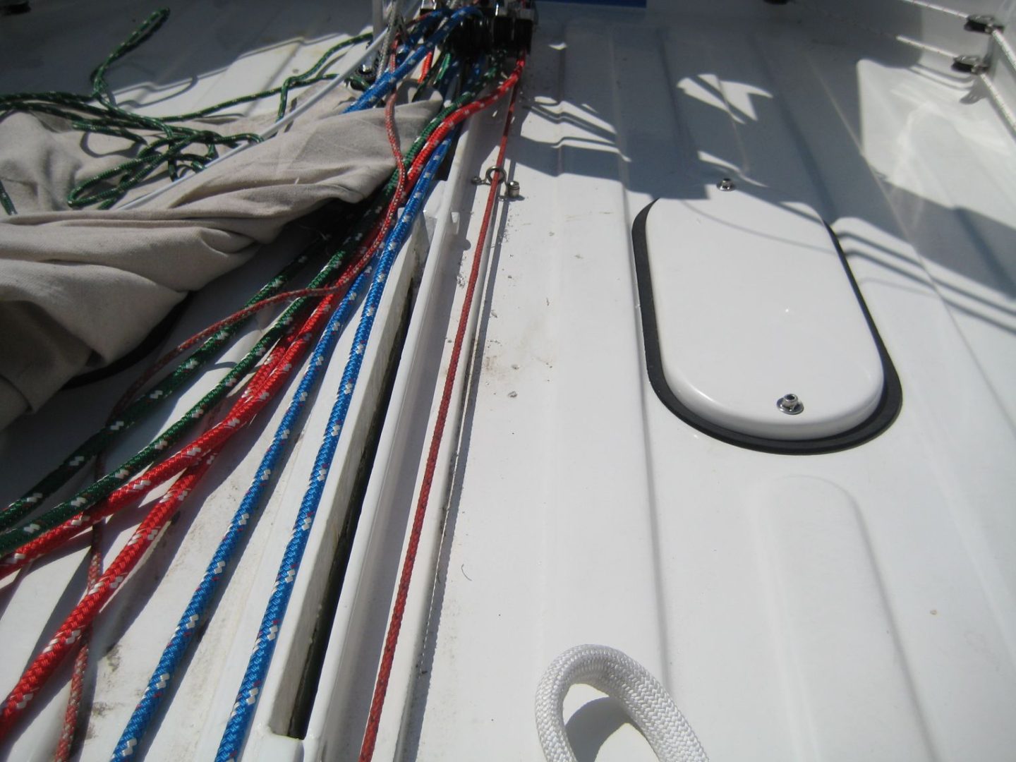 A boat with ropes and a pole on the deck.