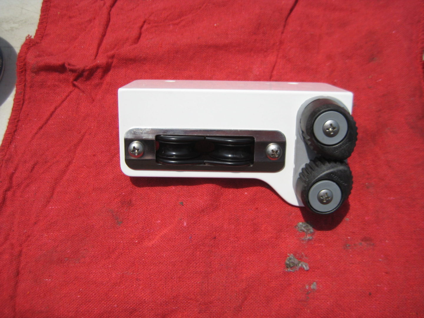 A white toy car with black wheels on top of red cloth.