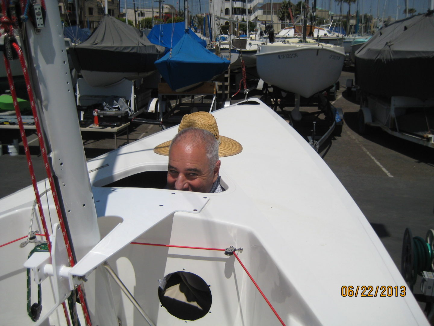 A man in a hat is looking out from the side of a boat.