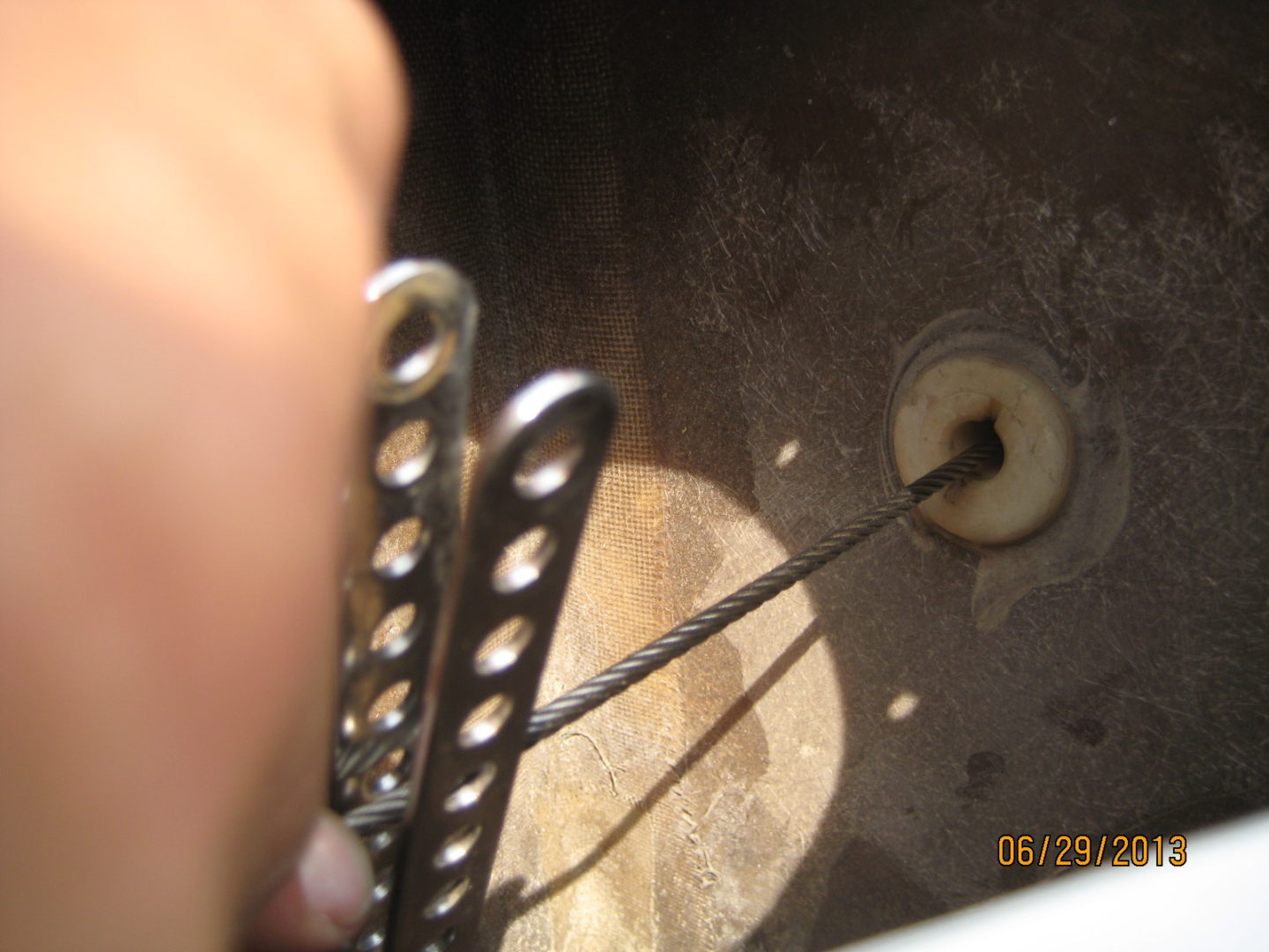 A person holding two metal forks over the top of a sink.